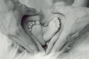 baby feet with daddy's hands making a heart around them