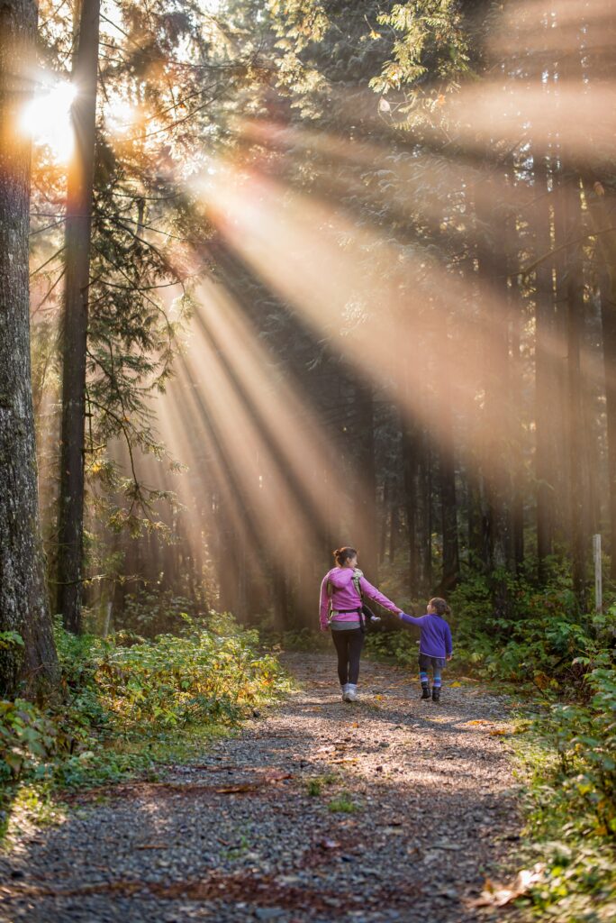 Mom and daughter holding hands and walking through the woods