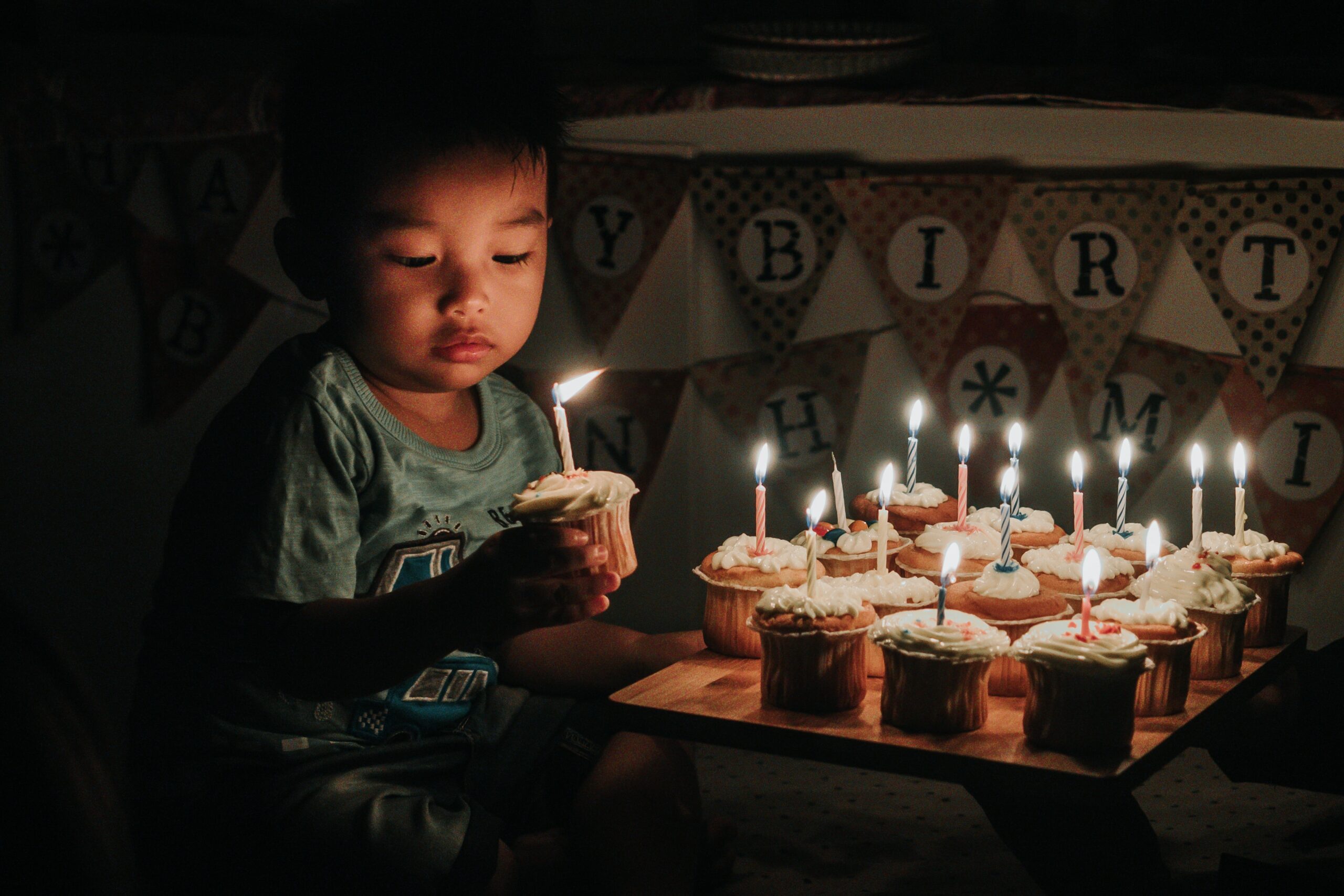 Child holding birthday cupcake with candle