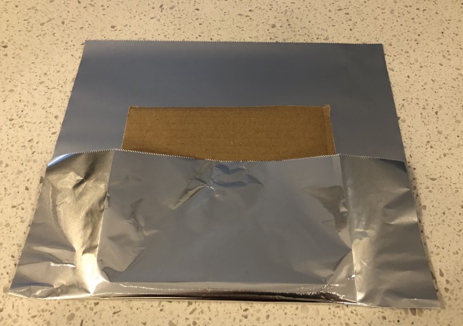 wrapping a gingerbread cardboard base with foil