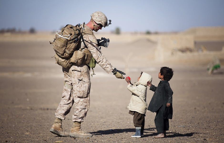 small child giving a flower to a soldier